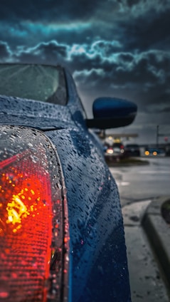 Close-up of a car roof covered in small dents from a recent hailstorm under a cloudy sky.
