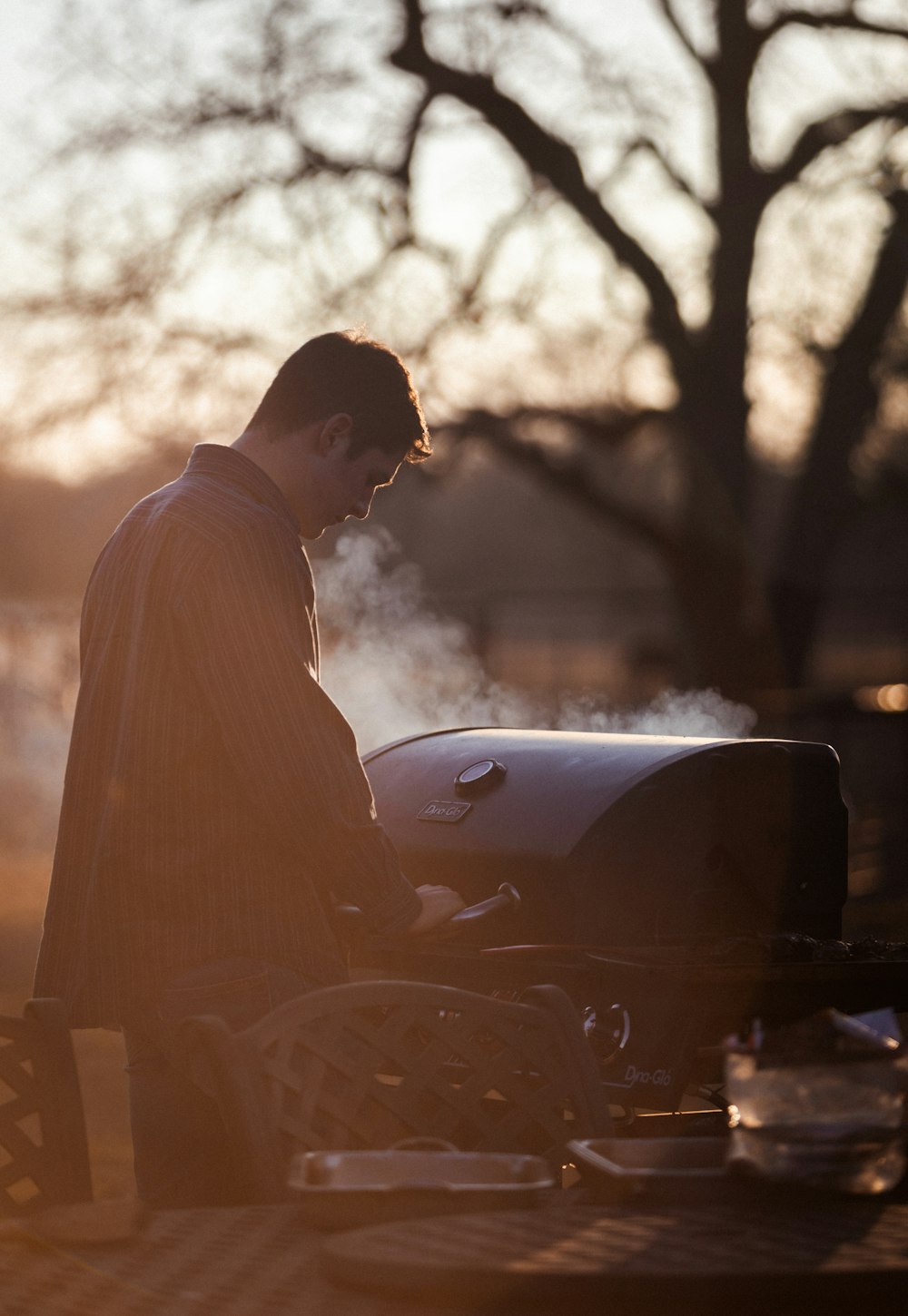 a man sitting on a bench next to a bbq