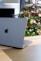an apple laptop sitting on a table in front of a christmas tree
