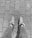 A pair of legs in leggings is visible, wearing sneakers with fur trim, standing on a paved brick pathway. The image is in black and white.