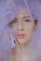 A soft-lit boudoir portrait of a woman wrapped in sheer fabric, highlighting natural beauty.