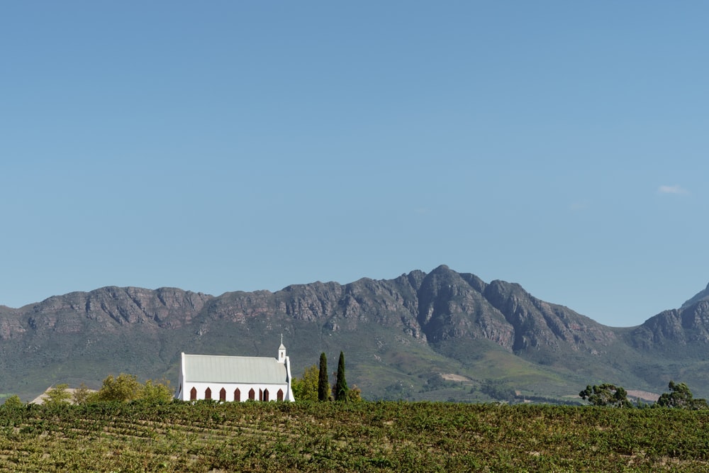 a church in the middle of a field with mountains in the background