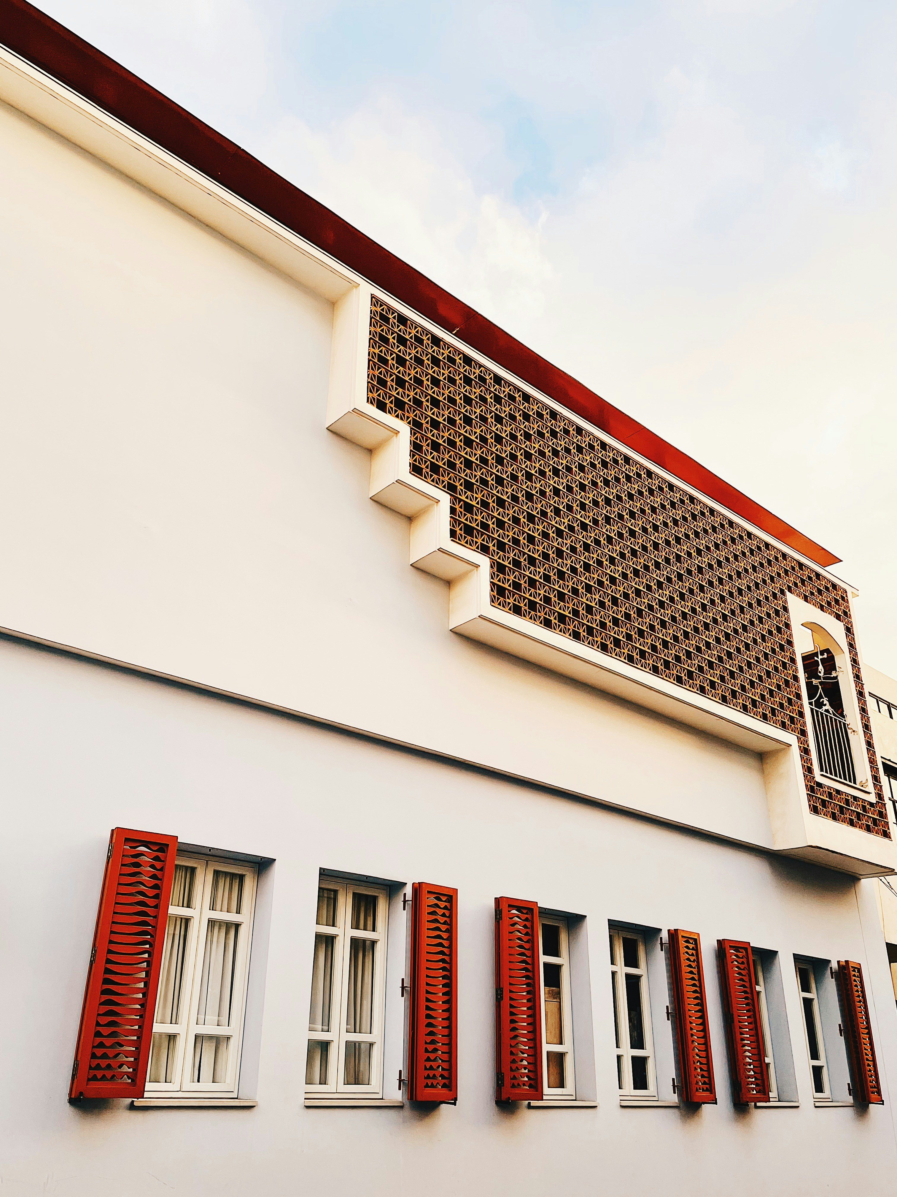 a white building with red shutters and a clock