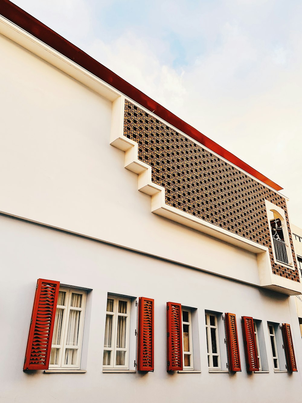 a white building with red shutters and a clock