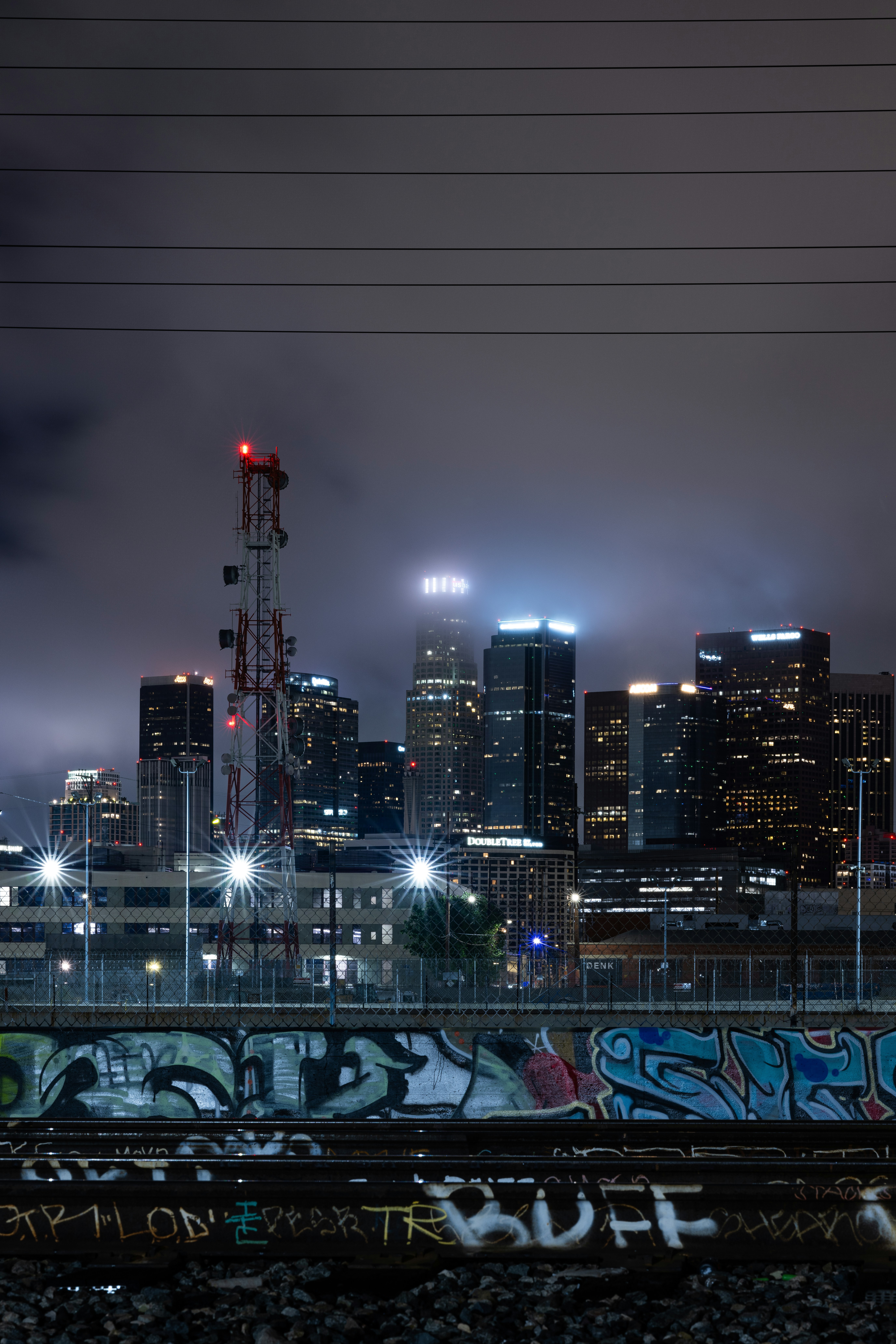 A city skyline at night with graffiti on the tracks photo – Free City Image  on Unsplash, image size:3000x4500