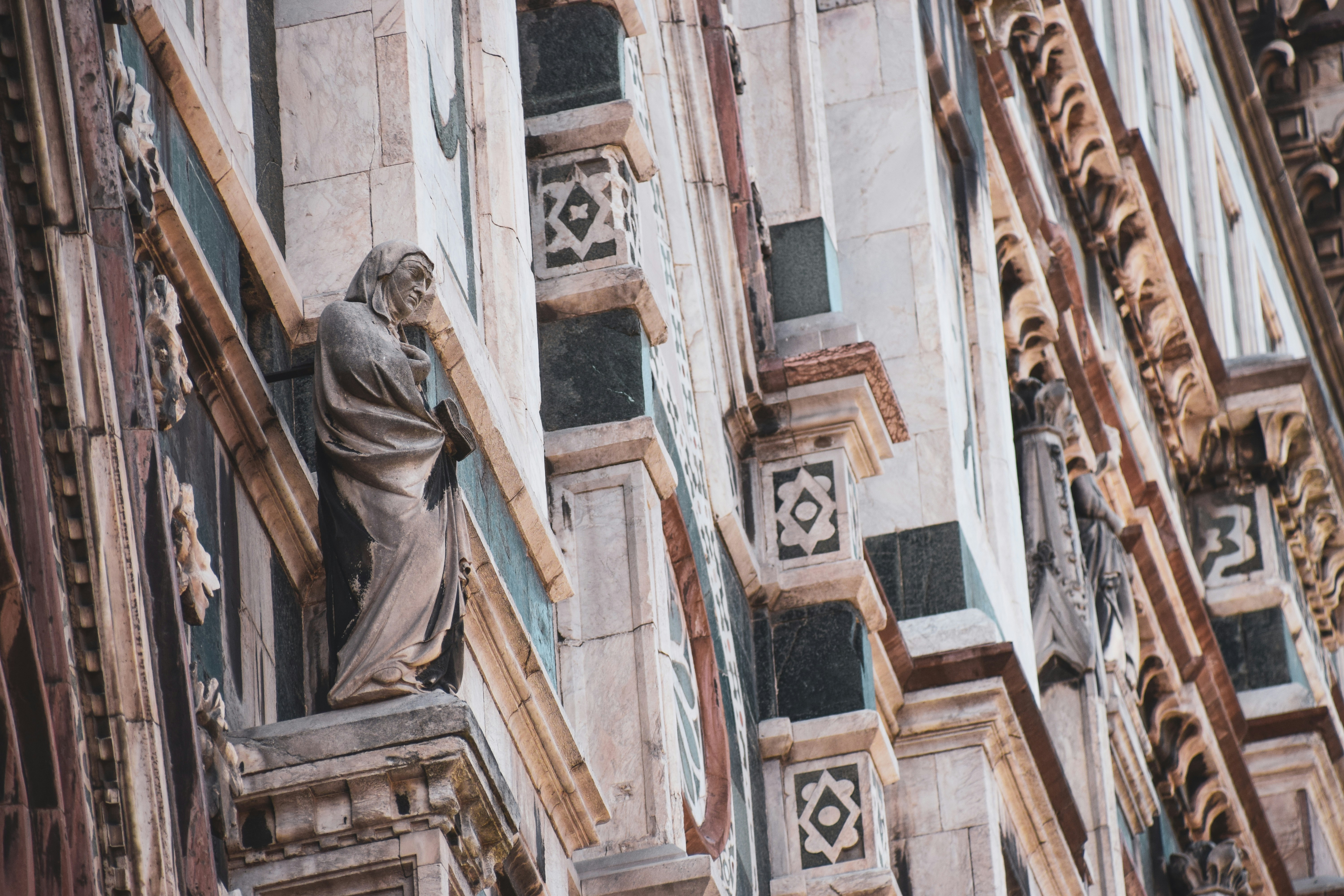 a statue of a man on a ledge of a building, the Santa Maria Cathedral in Florence, Italy