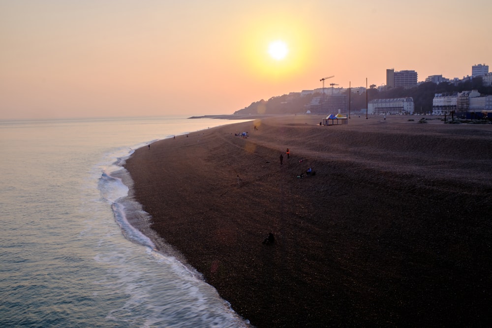 the sun is setting over the beach and the water