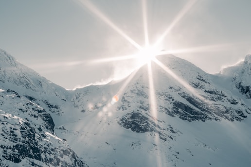 the sun shines brightly over a snowy mountain