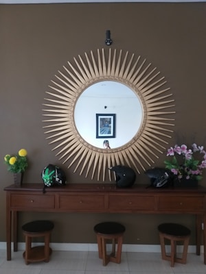 A stylish entryway featuring a sculptural mirror above a wooden console table adorned with artisan pottery and a leather catchall tray.