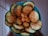 A bowl filled with sliced cucumbers sprinkled with a generous amount of chili powder. The slices are arranged in a circular pattern and appear fresh and crunchy.