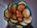 A bowl filled with sliced cucumbers sprinkled with a generous amount of chili powder. The slices are arranged in a circular pattern and appear fresh and crunchy.