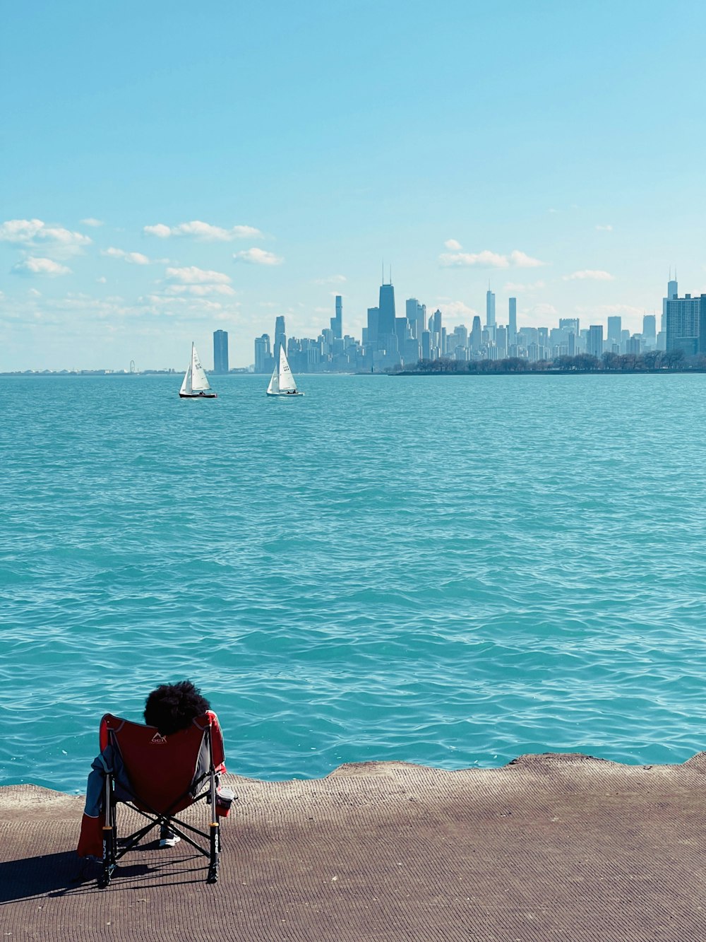 a person sitting in a chair on the edge of a pier