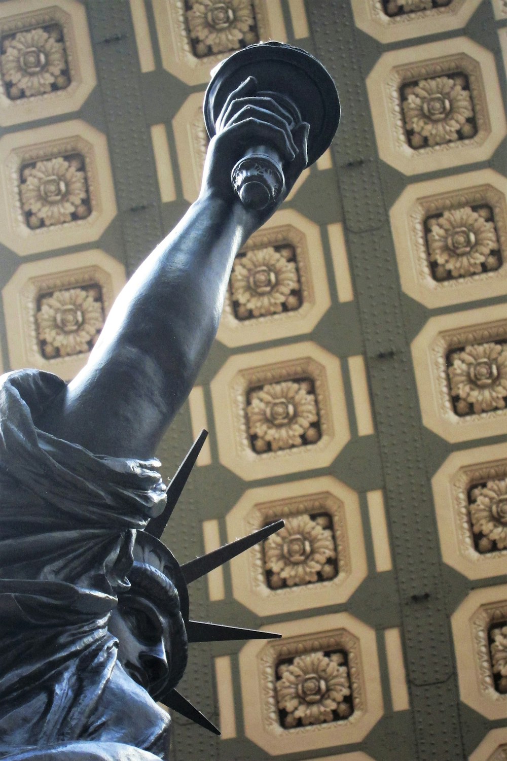 a statue of liberty in front of a wallpapered ceiling