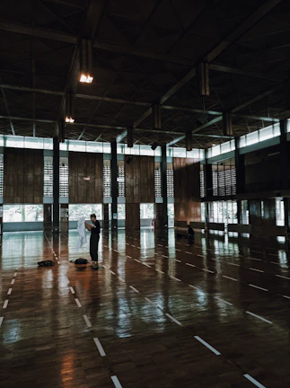 Modern indoor sports hall with freshly installed wooden flooring and basketball hoops.