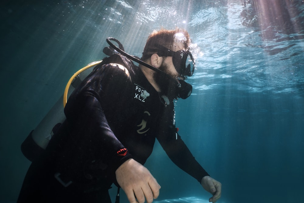 Un hombre con traje de neopreno y gafas nadando bajo el agua