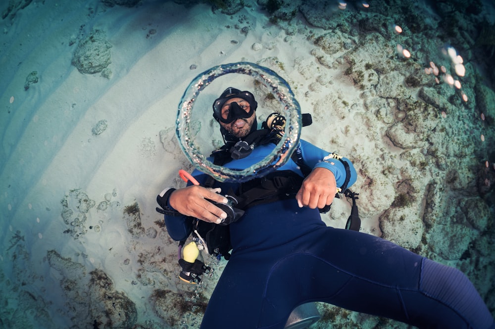 um homem em um traje de mergulho está segurando um objeto circular