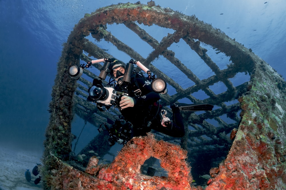 a man in a scuba suit taking a picture of a ship wreck