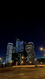 A sleek nighttime cityscape showcasing illuminated luxury high-rise buildings under a starry sky.