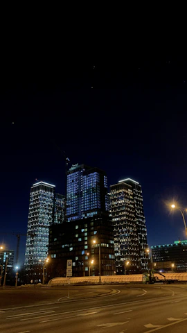 A sleek nighttime cityscape showcasing illuminated luxury high-rise buildings under a starry sky.