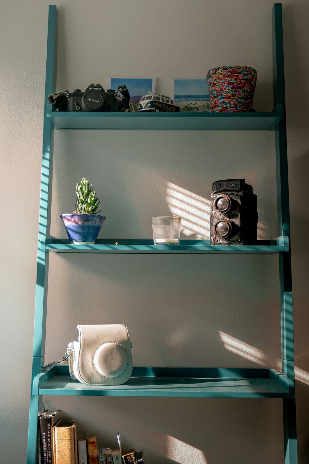 a shelf with a camera, a camera and a cup on it
