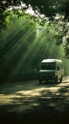a white van driving down a road surrounded by trees