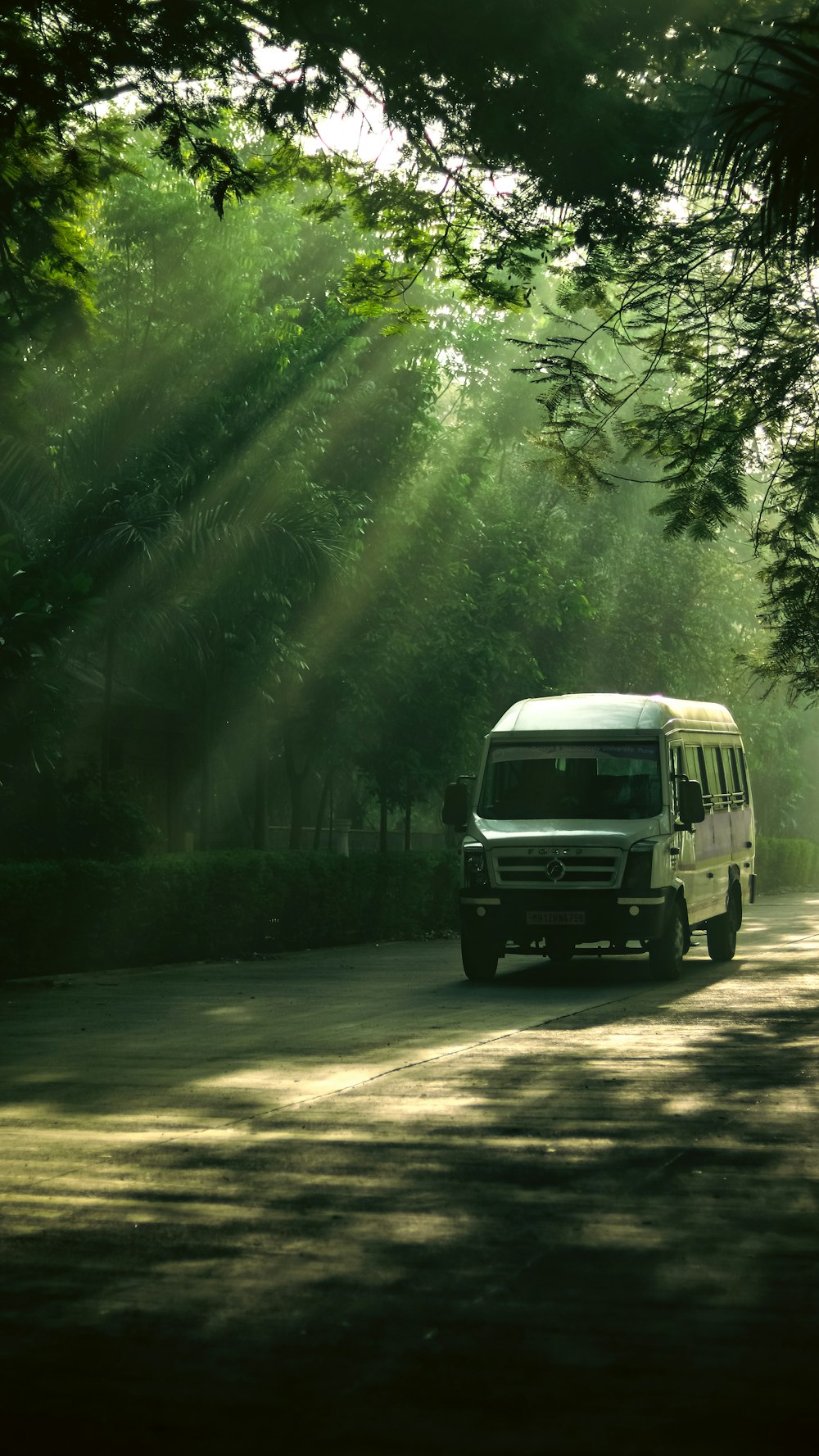a white van driving down a road surrounded by trees