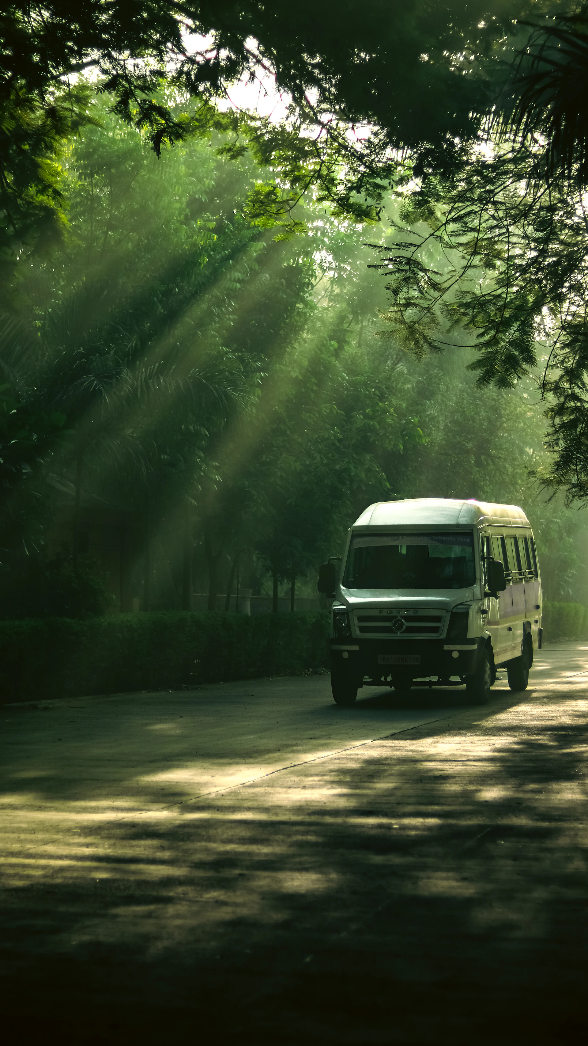 a white van driving down a road surrounded by trees