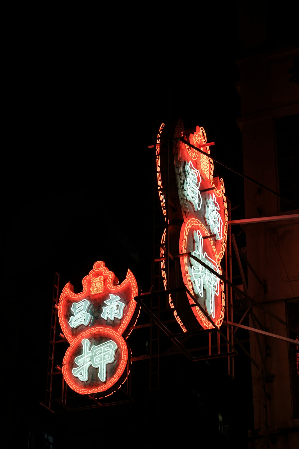 a couple of neon signs hanging from the side of a building