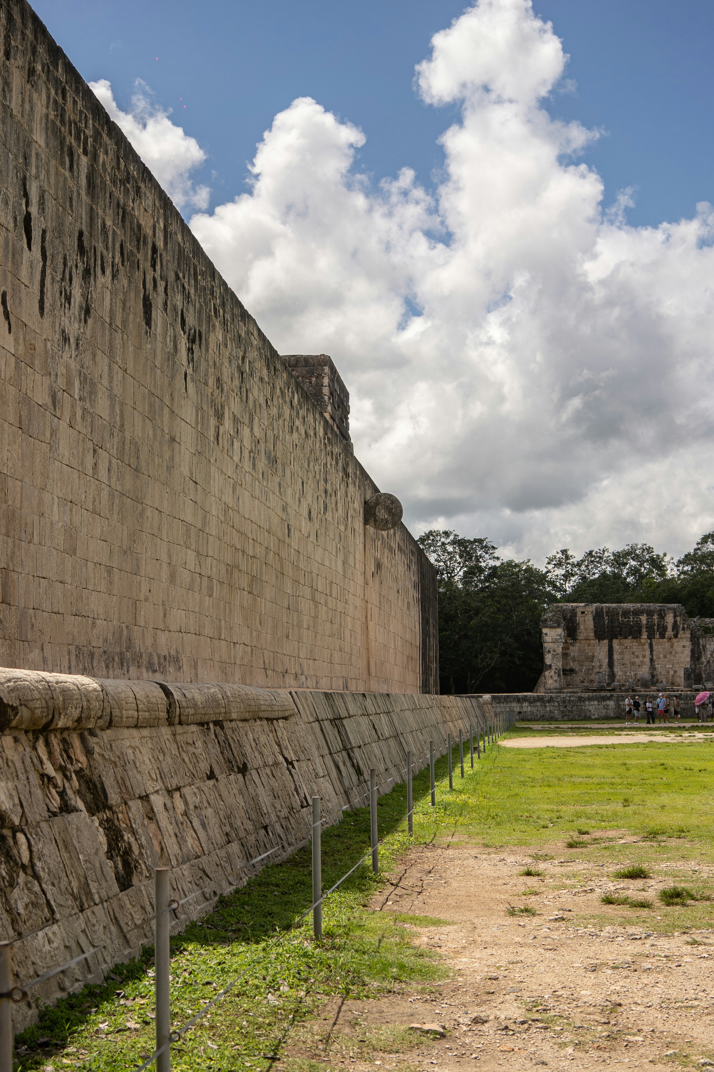 a large stone wall next to a grassy field