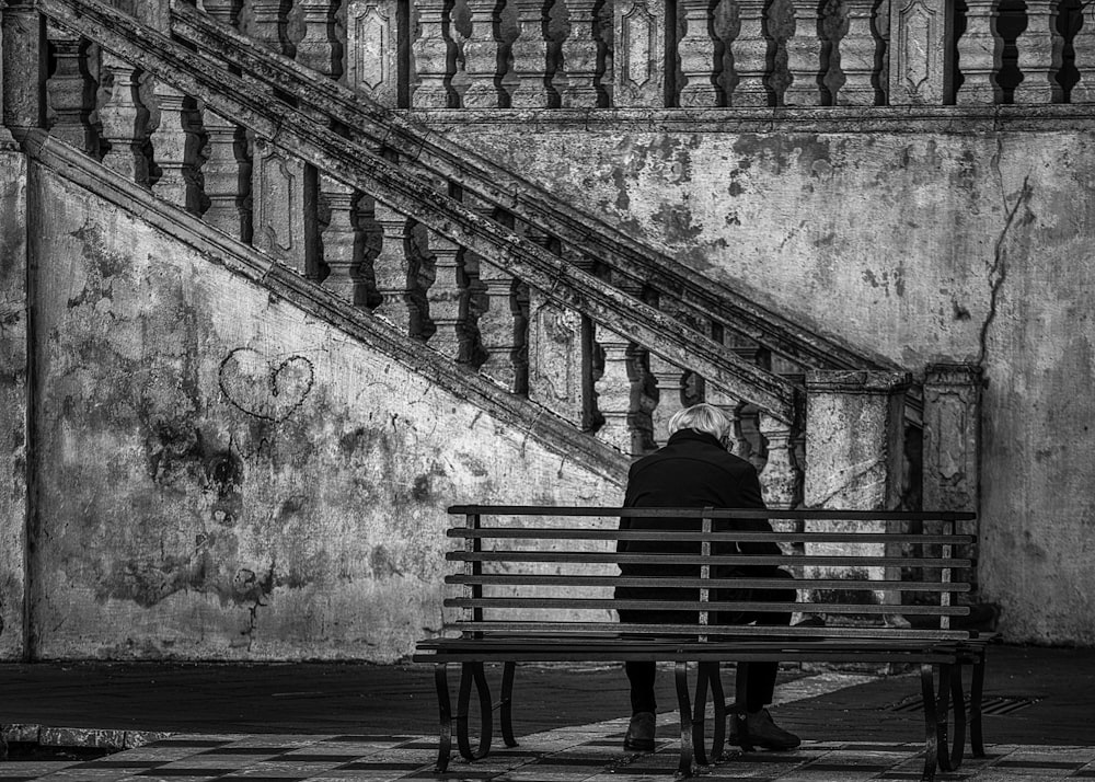 a man sitting on a bench in front of a stair case