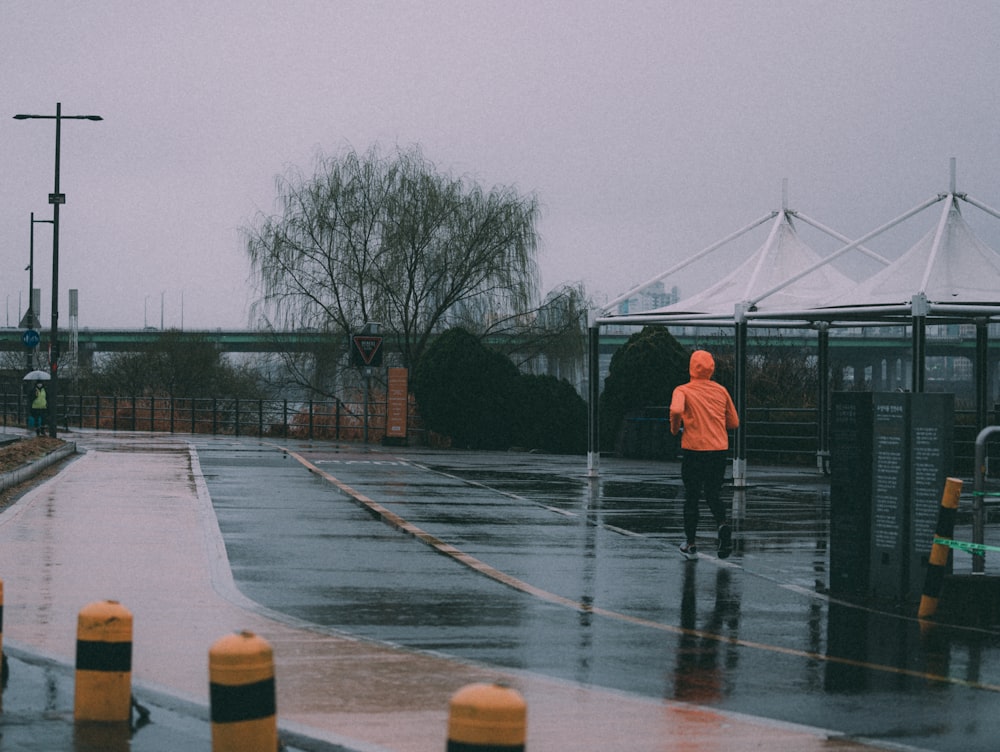 a person in an orange jacket is walking in the rain