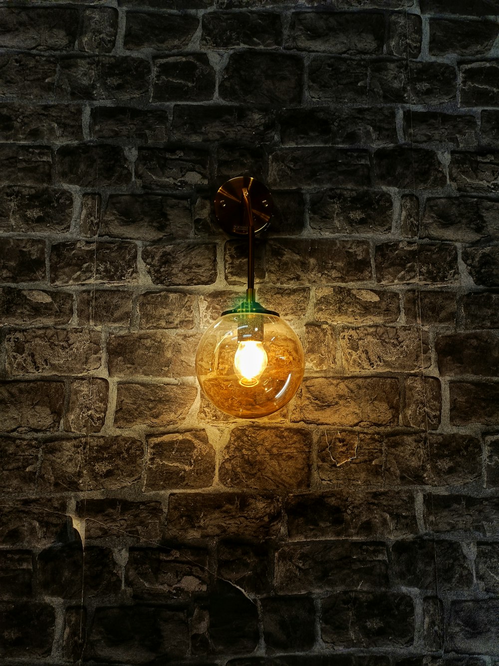 a light bulb hanging from the side of a brick wall