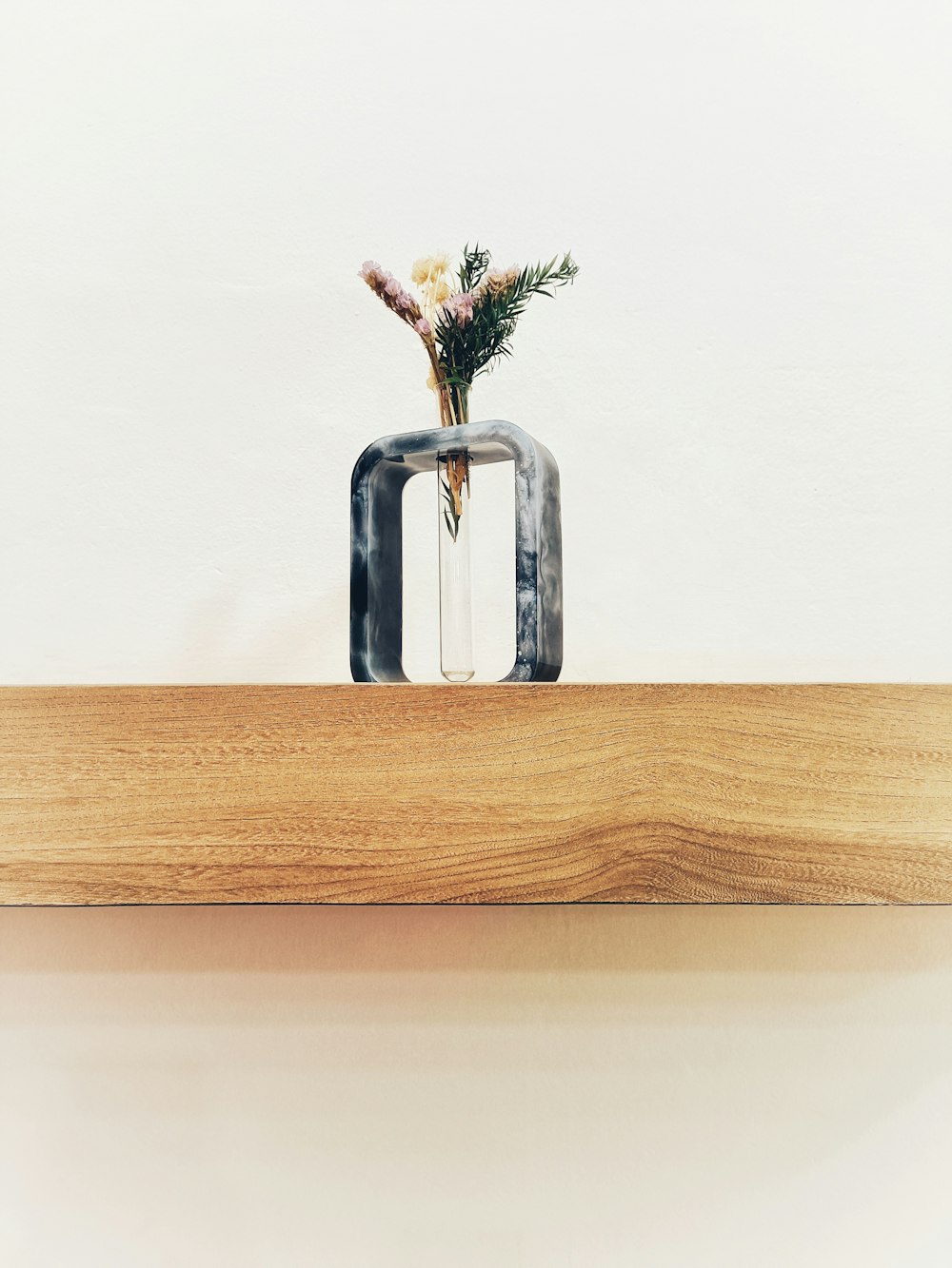a vase with flowers in it sitting on a shelf