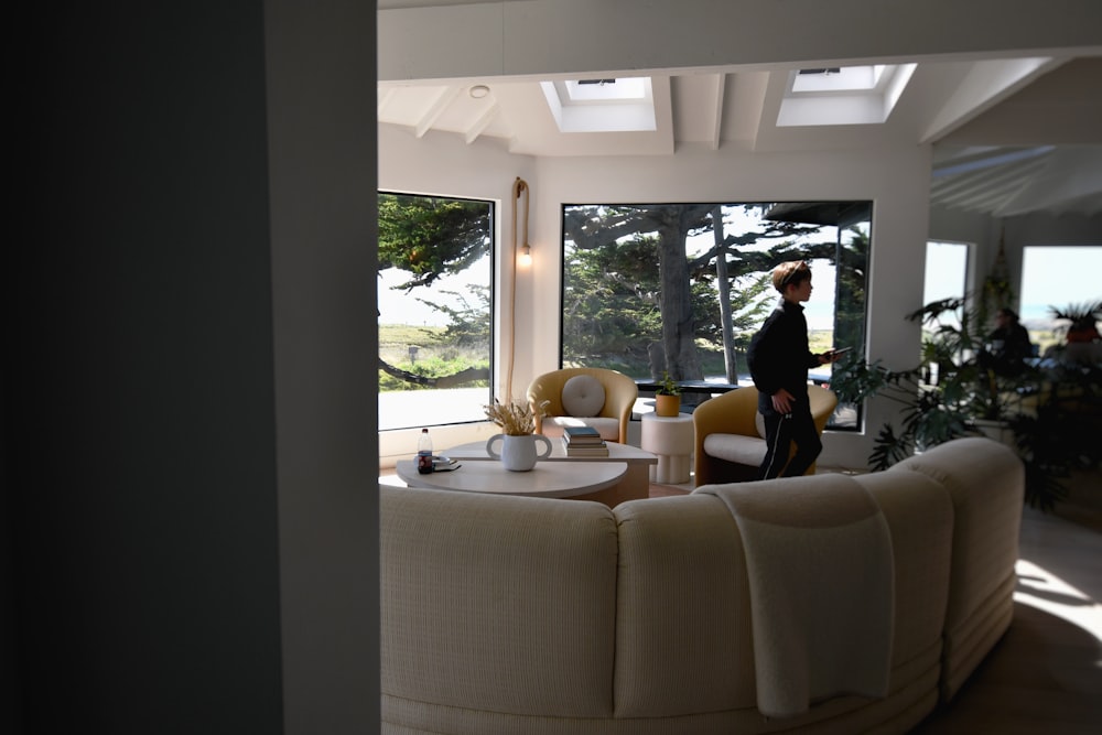 a woman standing in a living room next to a window