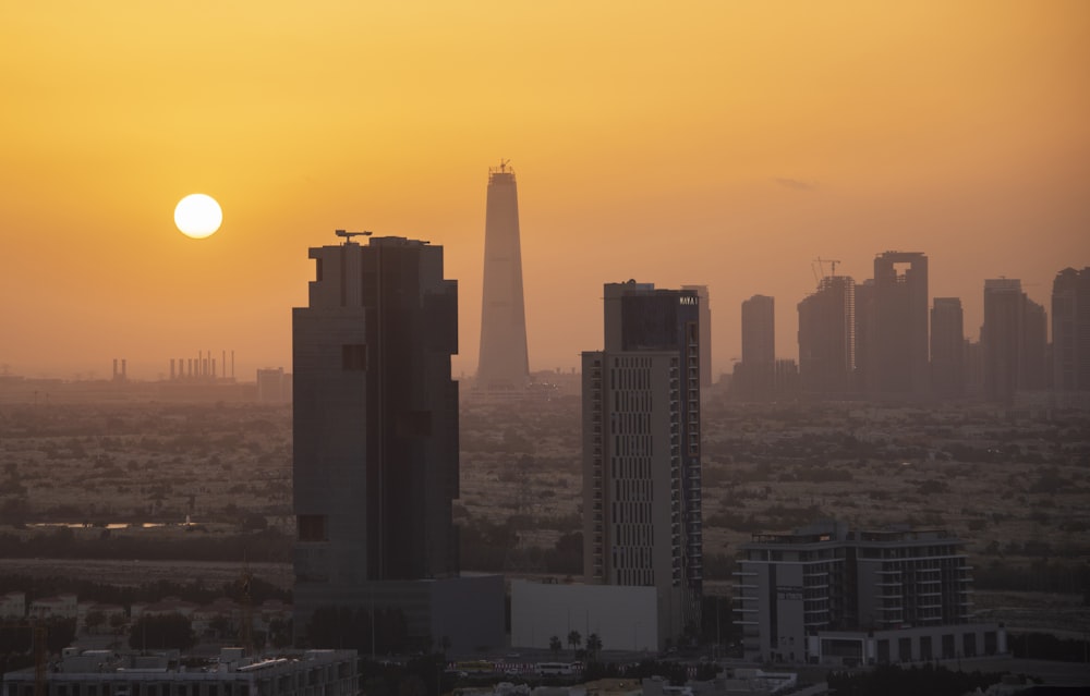 the sun is setting over a city with tall buildings