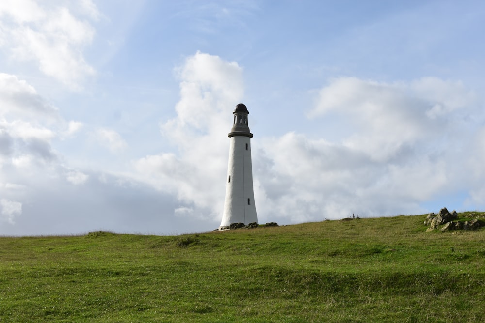 a white light house on a grassy hill
