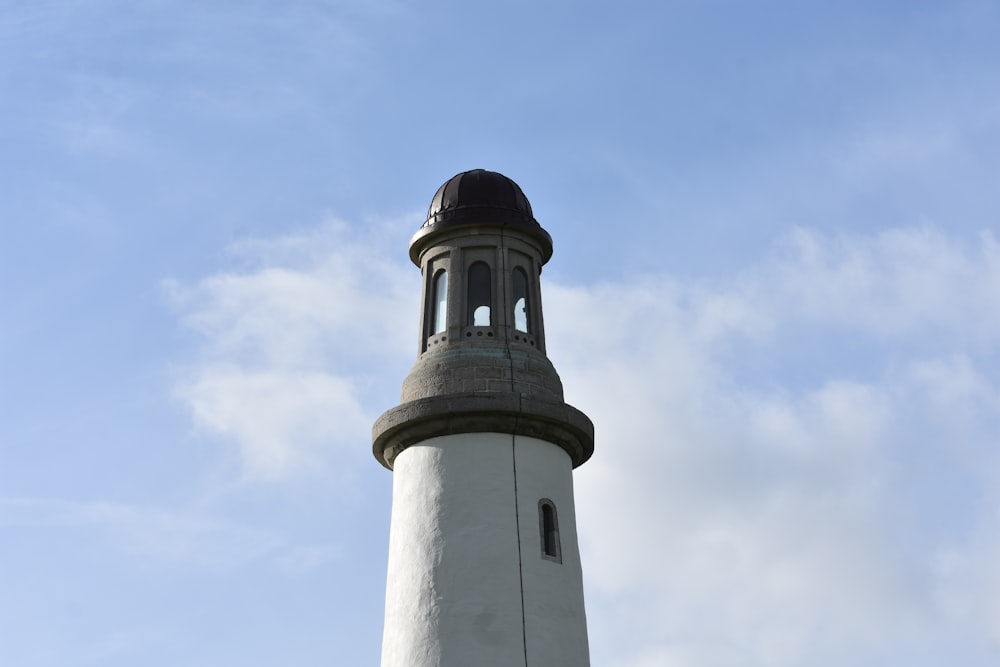 a white lighthouse with a brown top against a blue sky