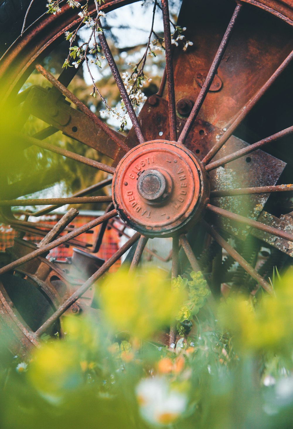 an old rusted wagon wheel in a field of flowers