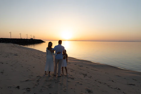 a family standing on a beach at sunset