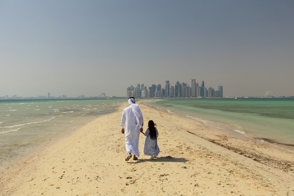 a man and a little girl are walking on the beach