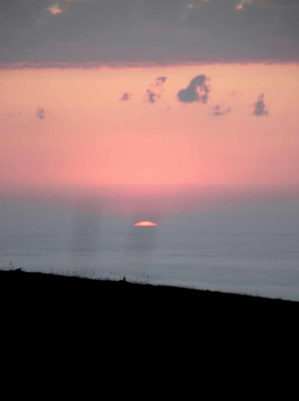 a silhouette of a person on a hill with a sunset in the background