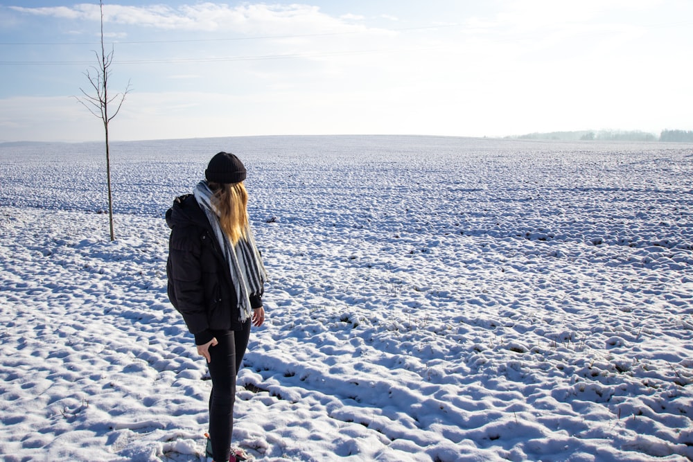 a woman standing in the middle of a snow covered field