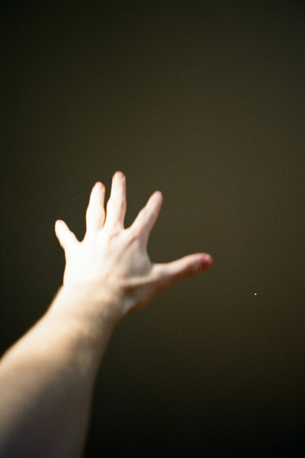 a person's hand reaching up to catch a frisbee