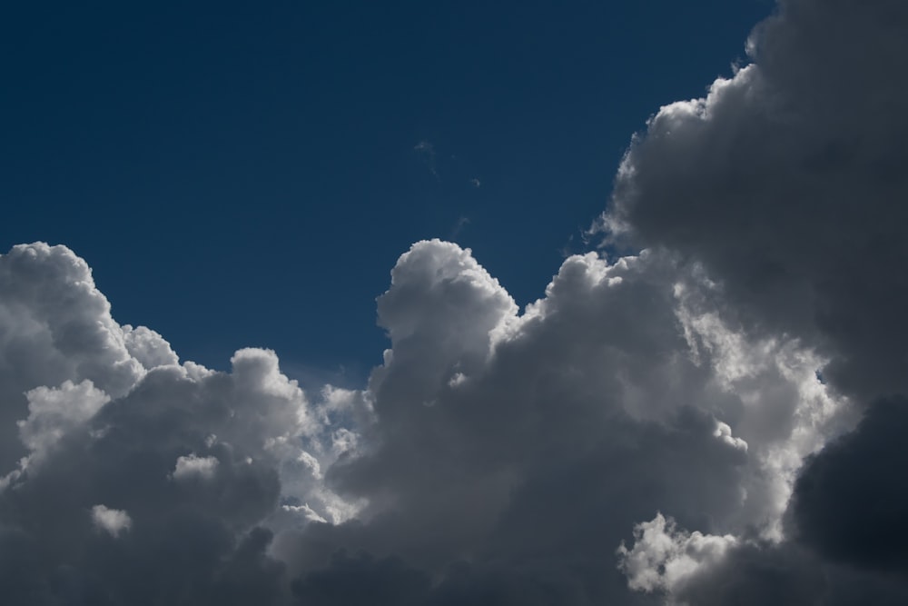 a plane flying through a cloudy blue sky