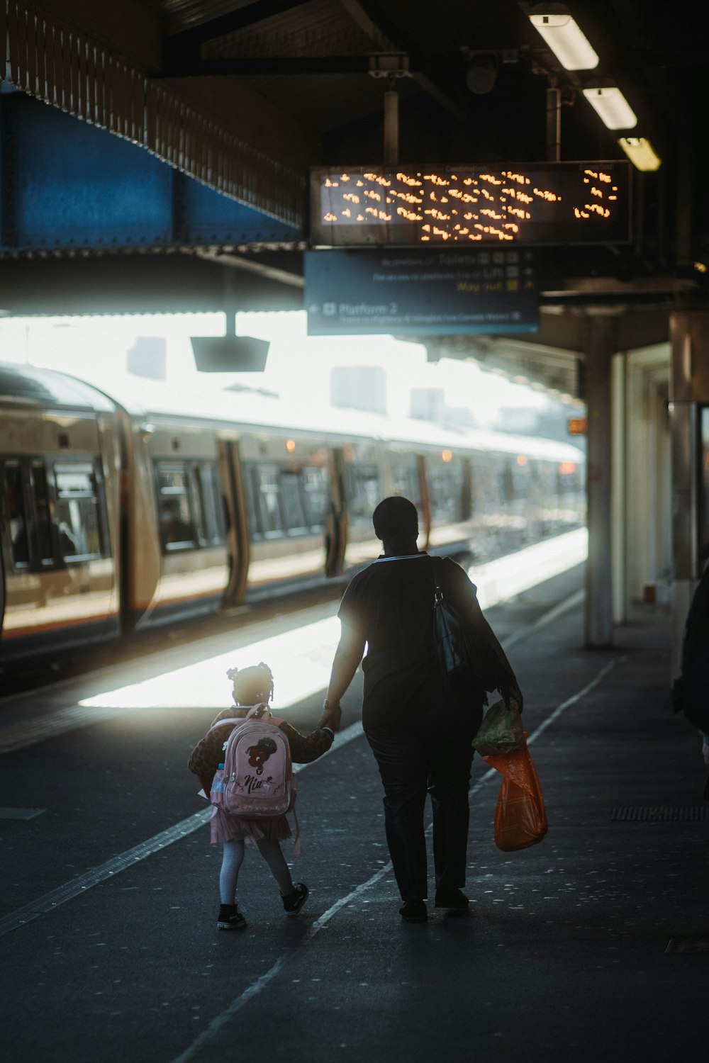 a man and a little girl are walking towards a train