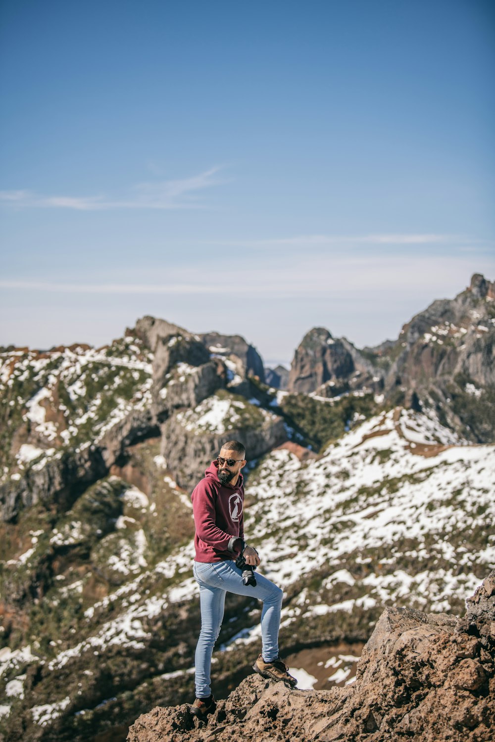 a man sitting on top of a mountain next to a snow covered mountain