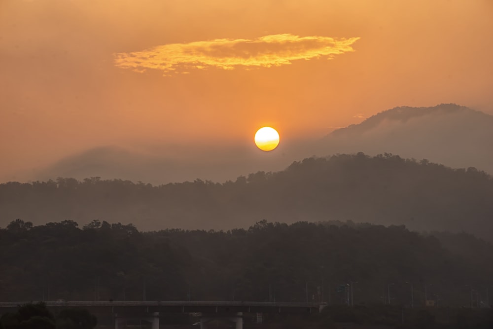 the sun is setting over a mountain range