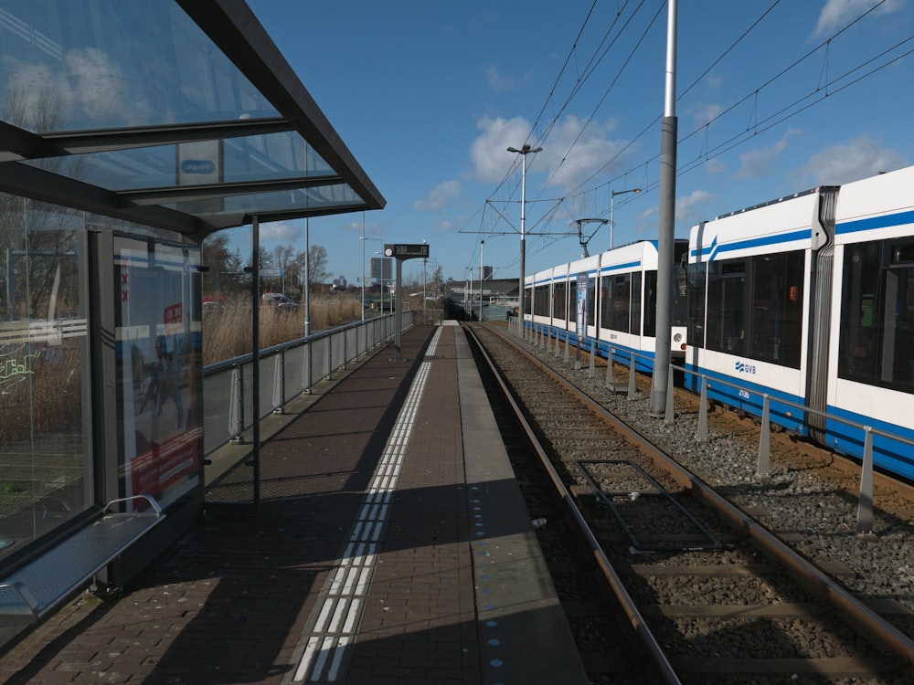 a blue and white train traveling past a train station