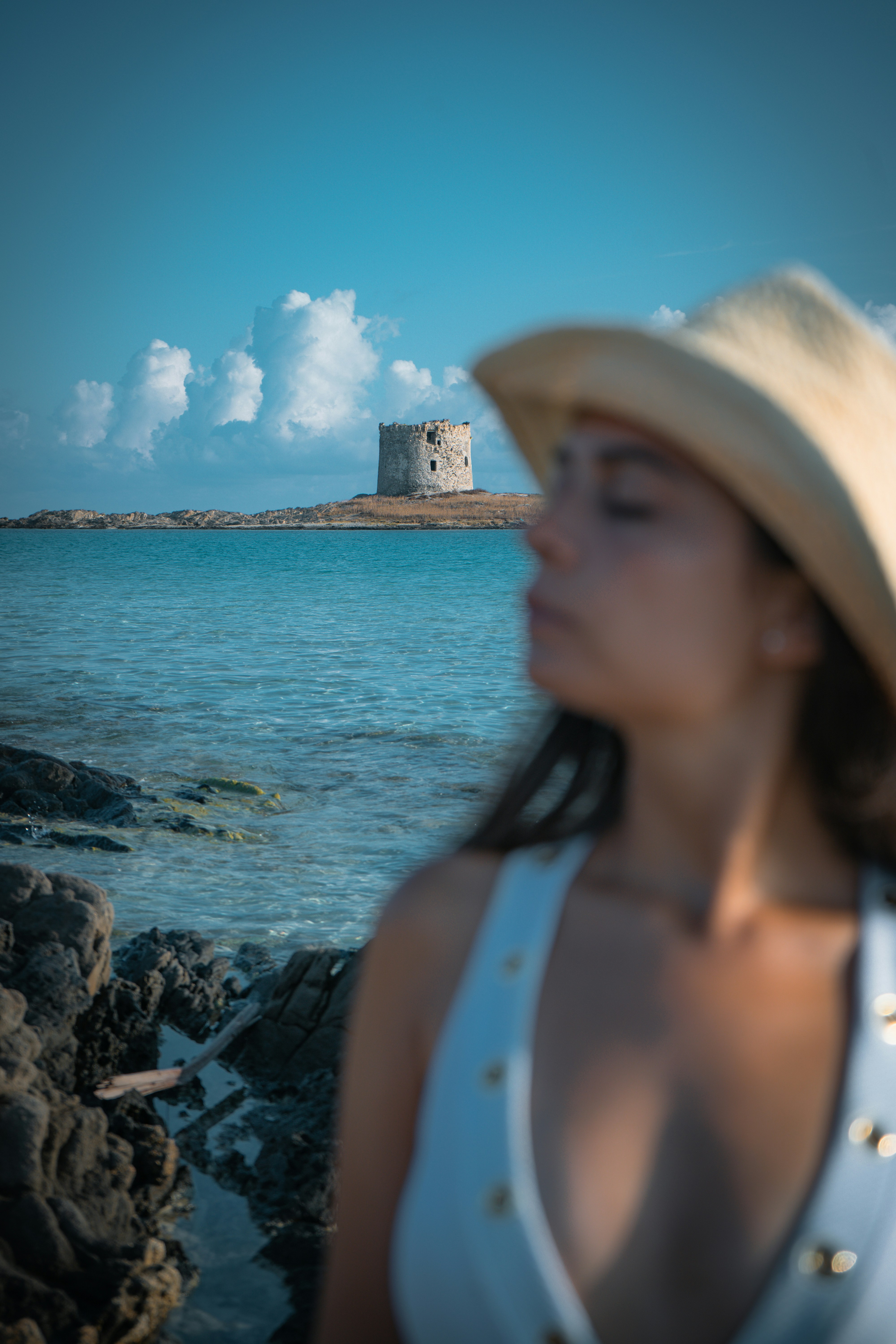 Woman in hat by the sea with tower