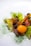 A gourmet dish featuring a vibrant yellow cherry tomato, surrounded by tender slices of cooked meat and lush green lettuce leaves. Garnished with dark berries and sprinkled finely with green herbs, adding a touch of elegance and freshness.